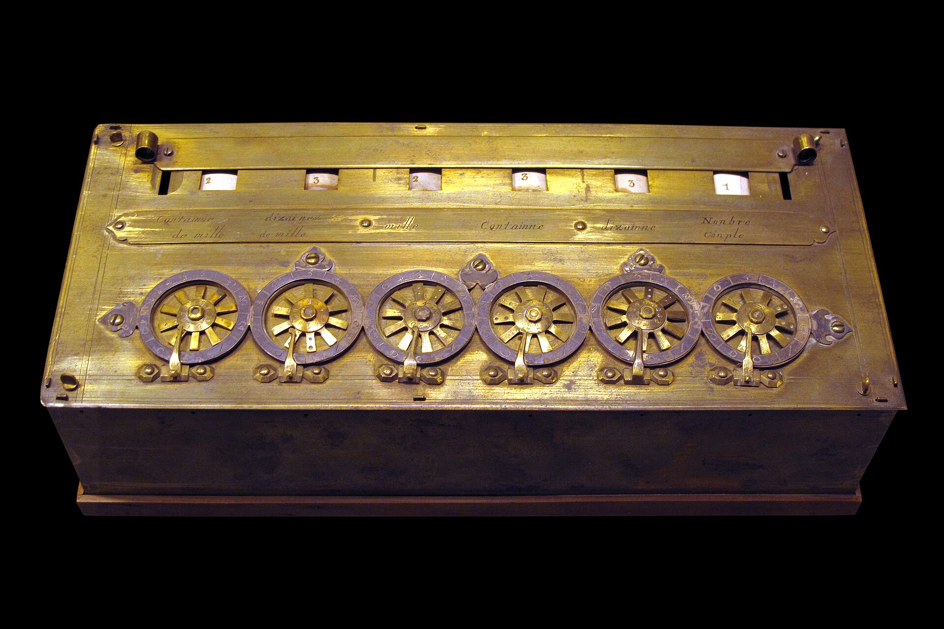 A Pascaline mechanical calculator displayed against a dark background.